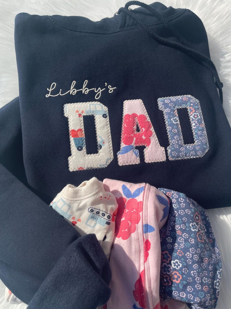 Blue sweatshirt with appliqué patch letters reading “Libby’s Dad” in floral fabric design