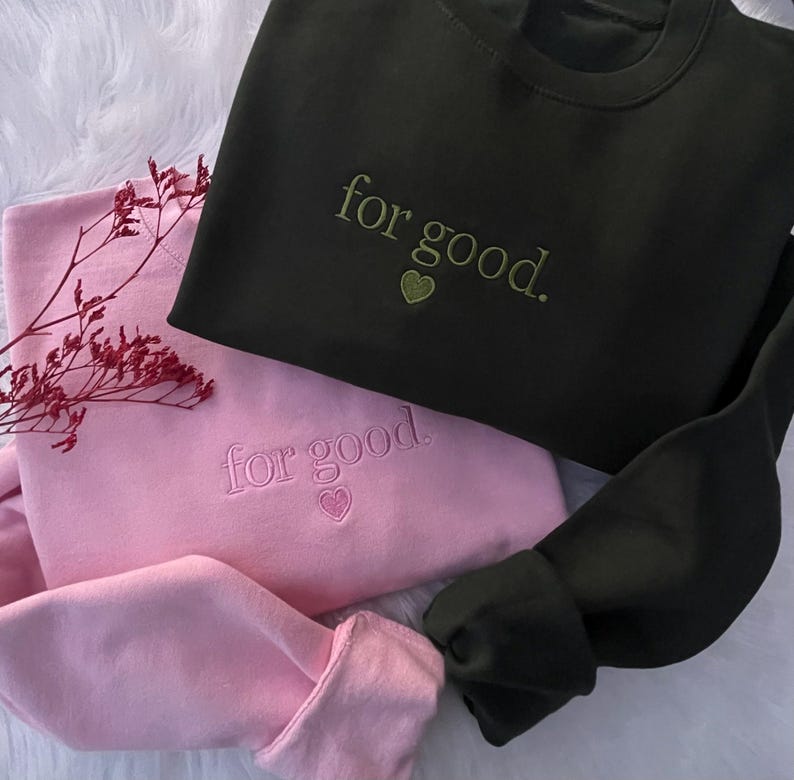 Green and pink sweatshirts with “For Good.” Wicked-inspired embroidered quote