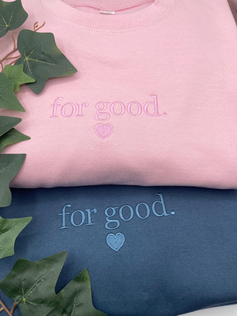 Pink and blue embroidered sweatshirts with “For Good.” heart design
