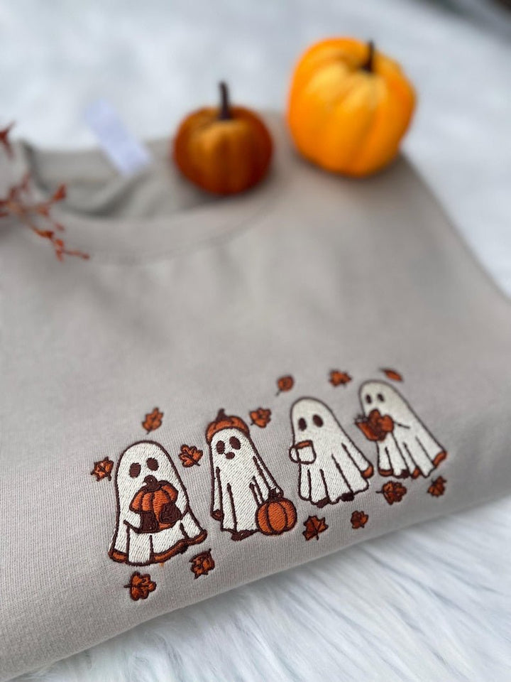 Beige sweatshirt with embroidered ghosts and autumn leaves, styled with pumpkins