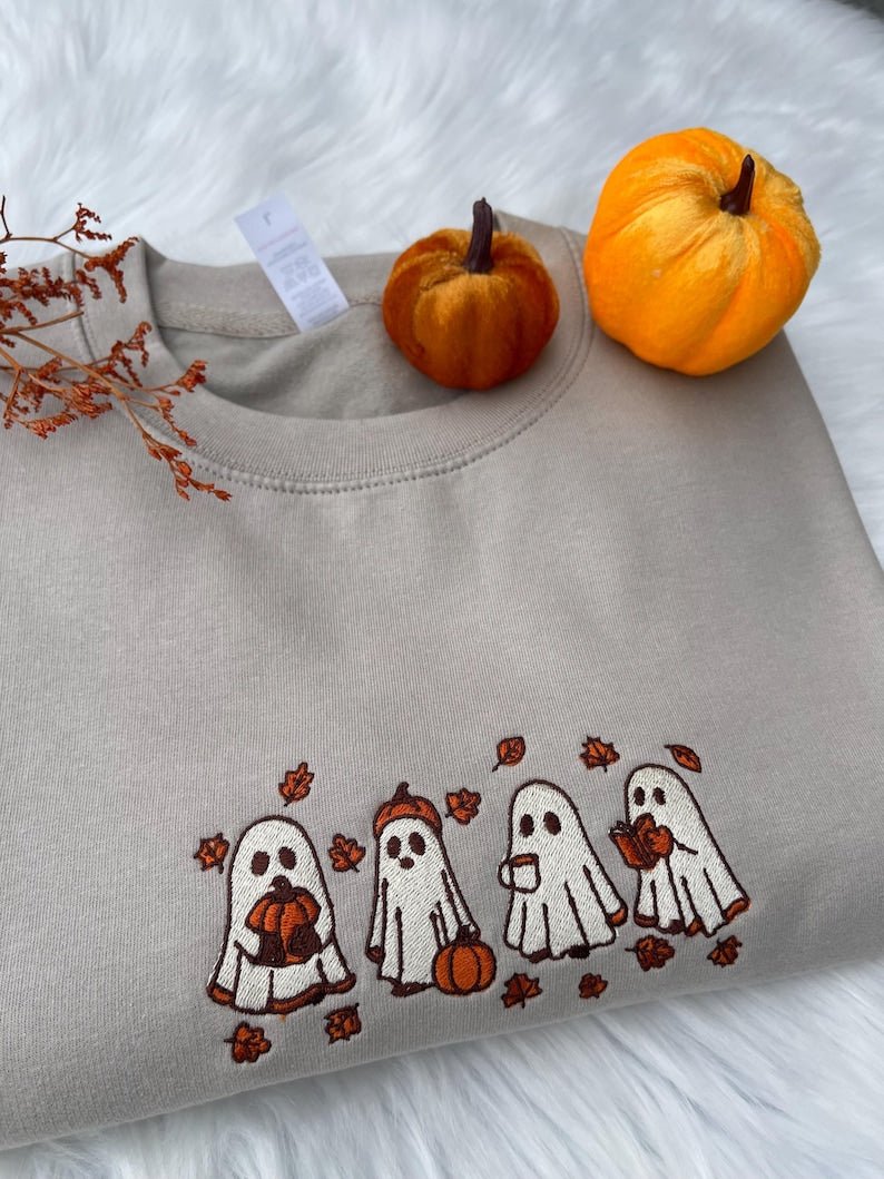 Beige sweatshirt folded with embroidered Halloween ghost and pumpkin design