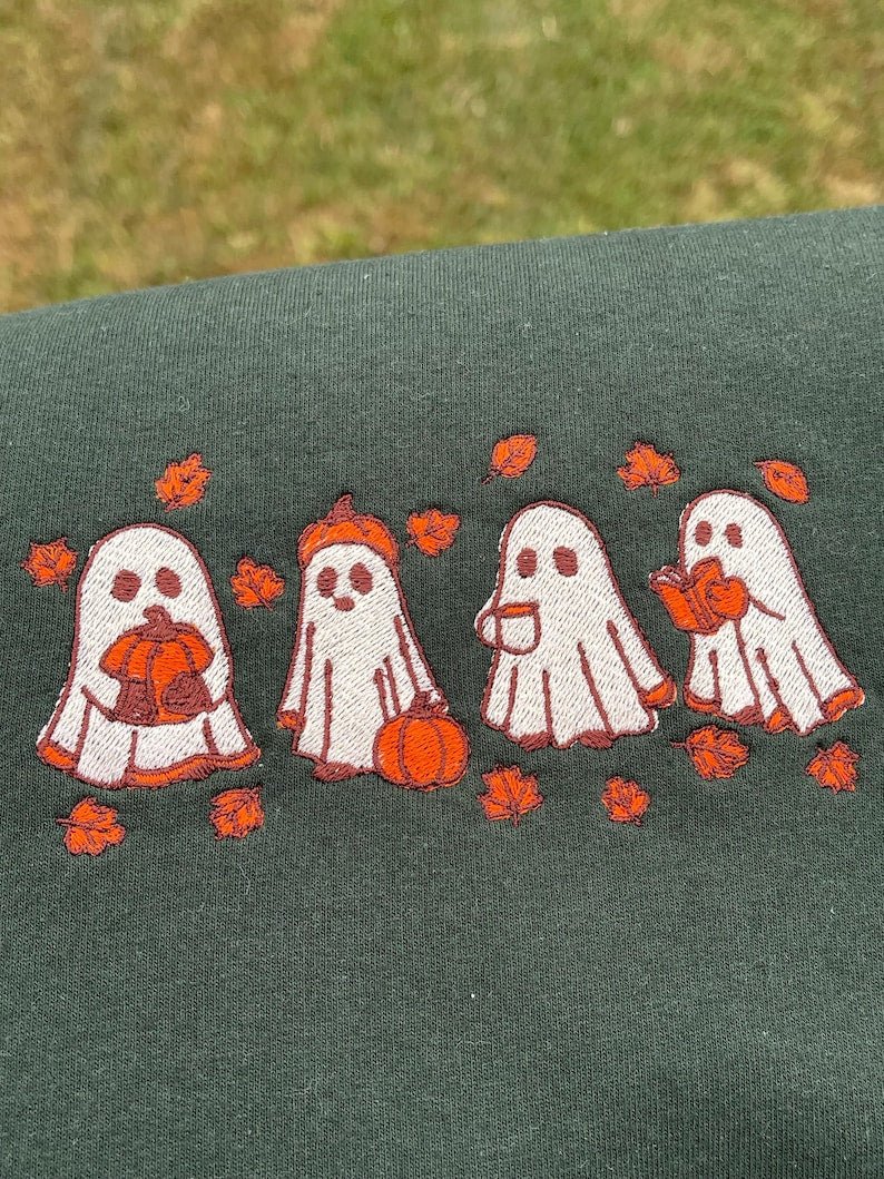 Green sweatshirt featuring embroidered Halloween ghost pattern with autumn leaves