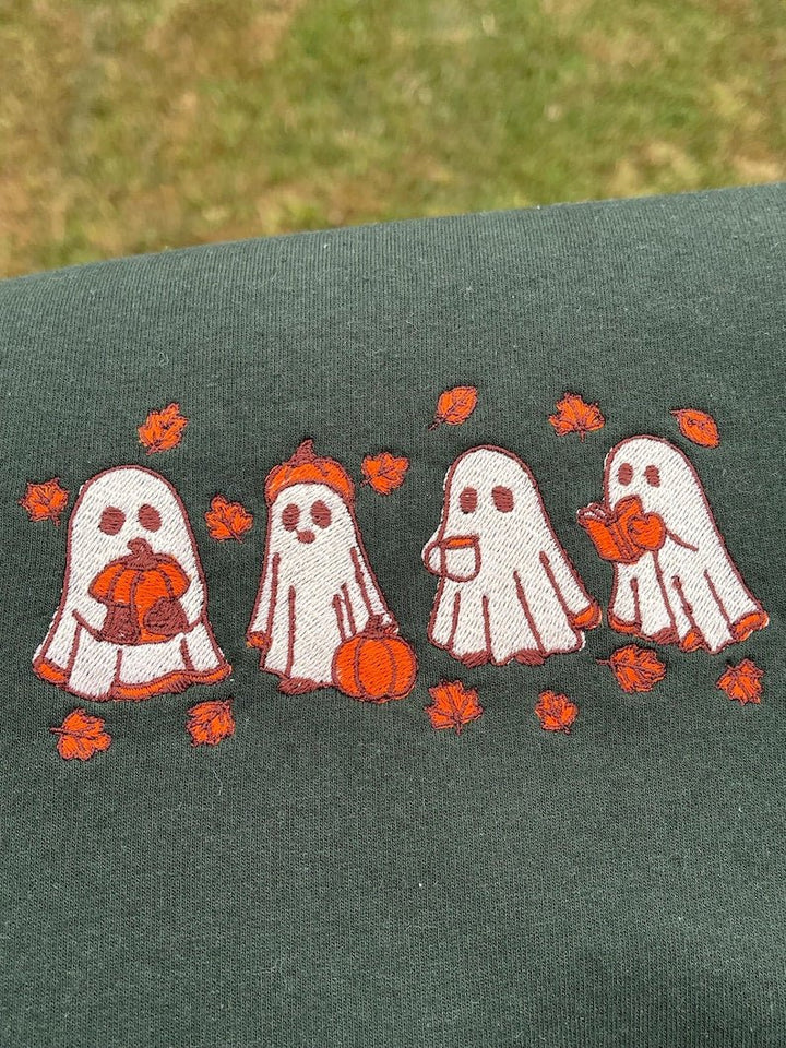 Green sweatshirt featuring embroidered Halloween ghost pattern with autumn leaves