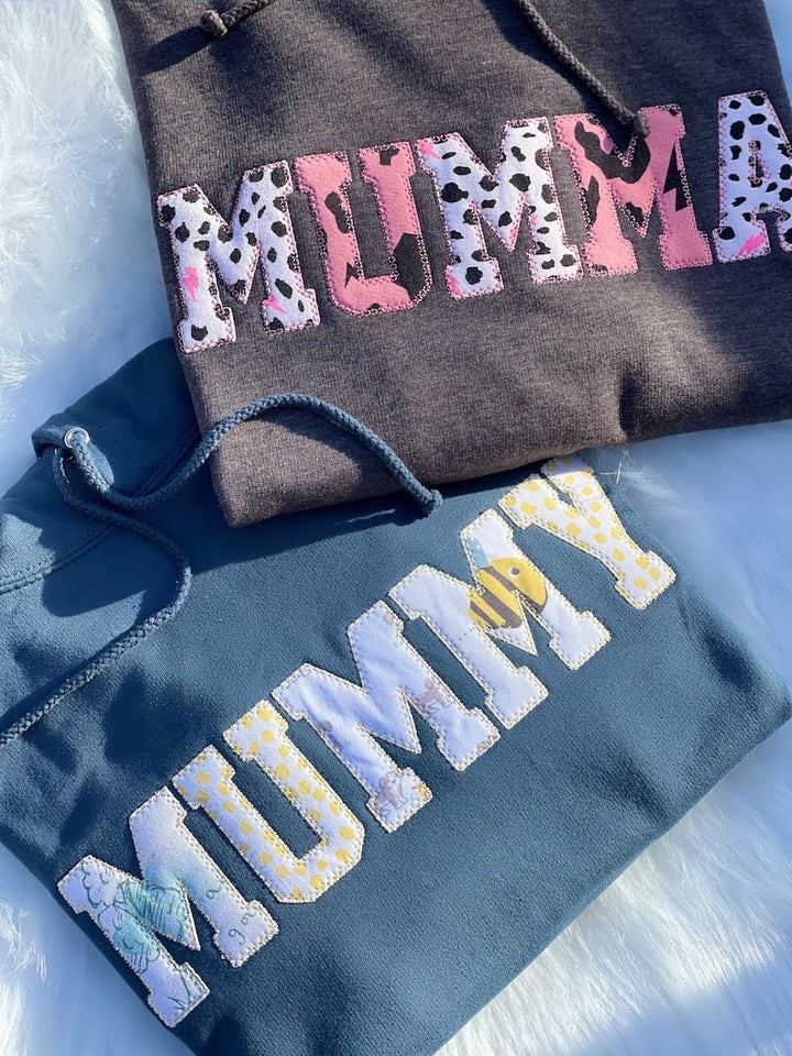 Black and navy sweatshirts with applique “MUMMY” text in patterned fabrics