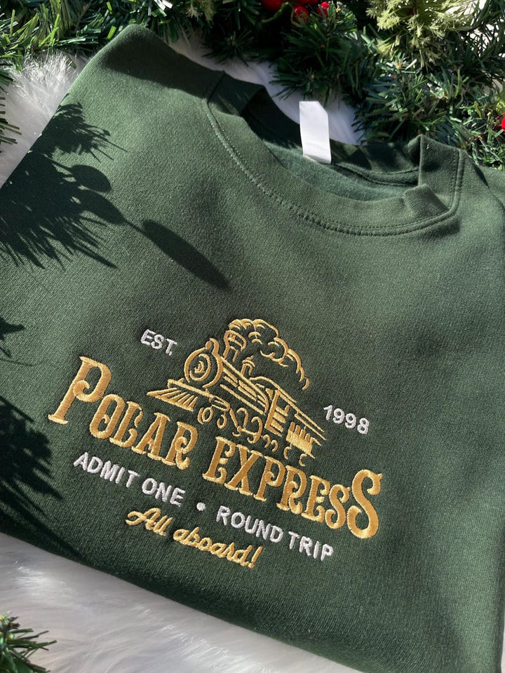 Green sweatshirt with embroidered Polar Express train and ticket design, styled with Christmas garland