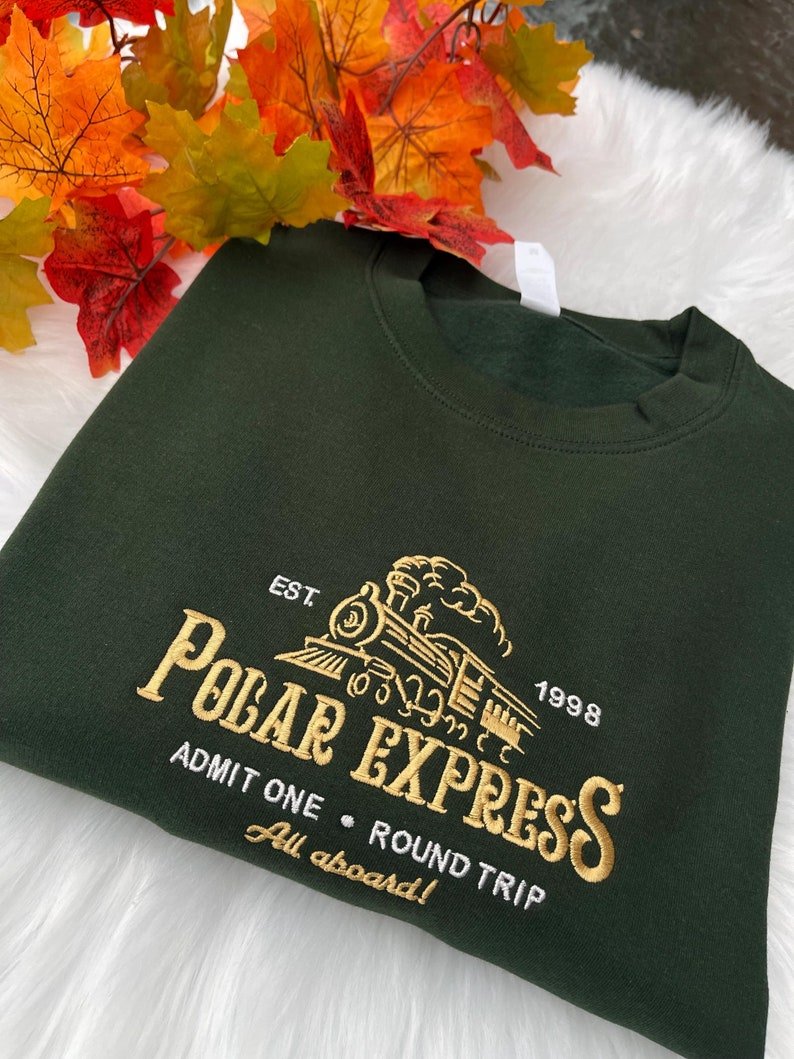 Green sweatshirt with Polar Express embroidery, styled with autumn decor