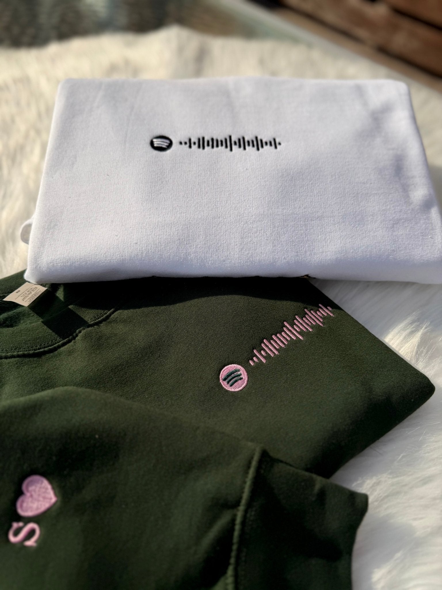 White and green sweatshirts with custom Spotify code embroidery.