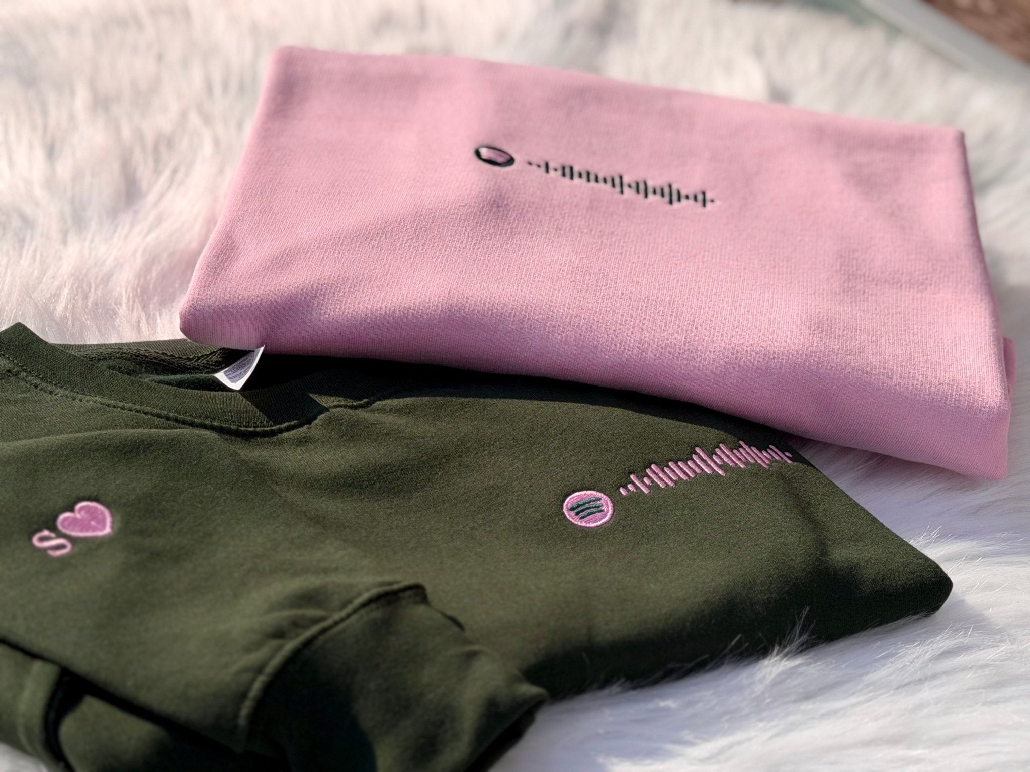 Green and pink embroidered sweatshirts with Spotify code design.