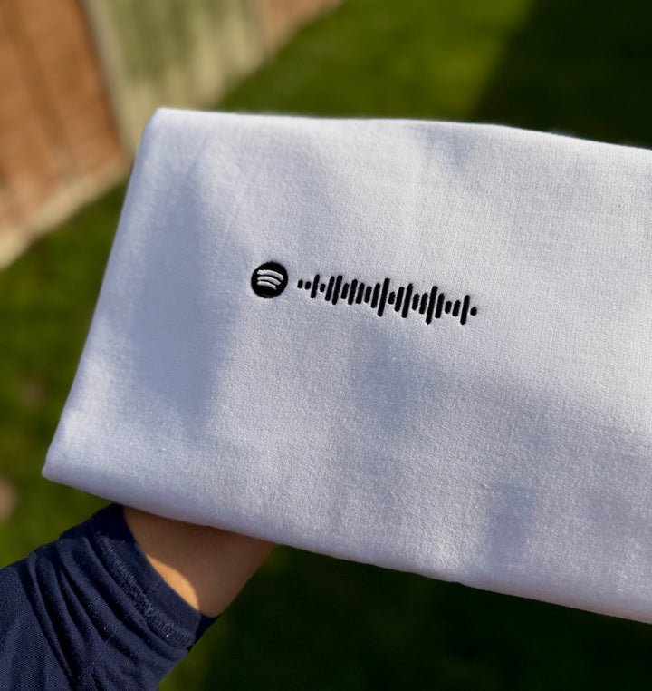 Close-up of white sweatshirt featuring custom Spotify code embroidery.